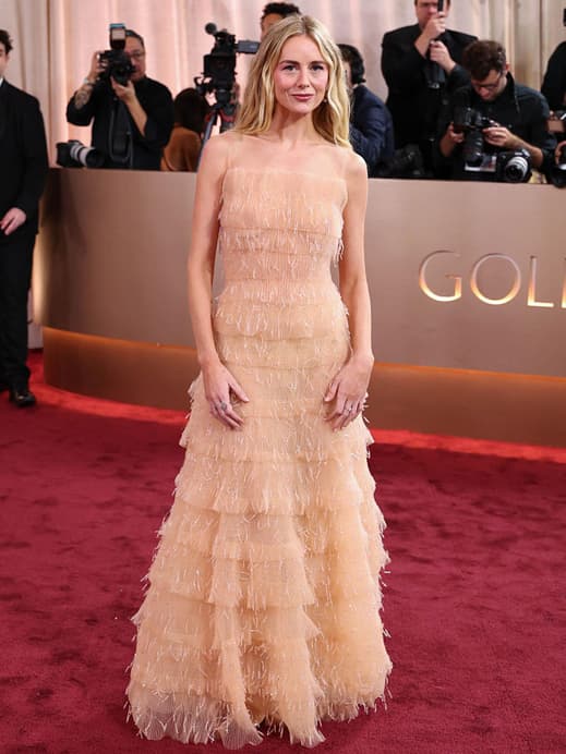 Justine Lupe in einem bodenlangen, nudefarbenen Kleid mit Fransen.