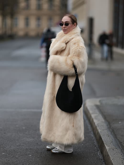 Frau in dickem Fellmantel mit großer Slouchy Bag