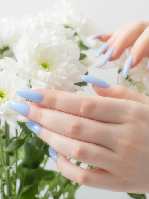 Hände mit hellblauen Nägeln und weiße Blumen