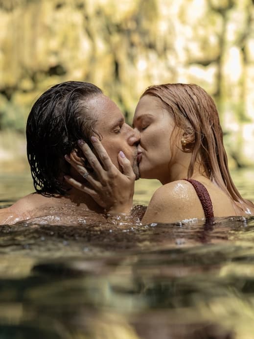 Ein Mann und eine Frau schwimmen im Wasser und küssen sich.