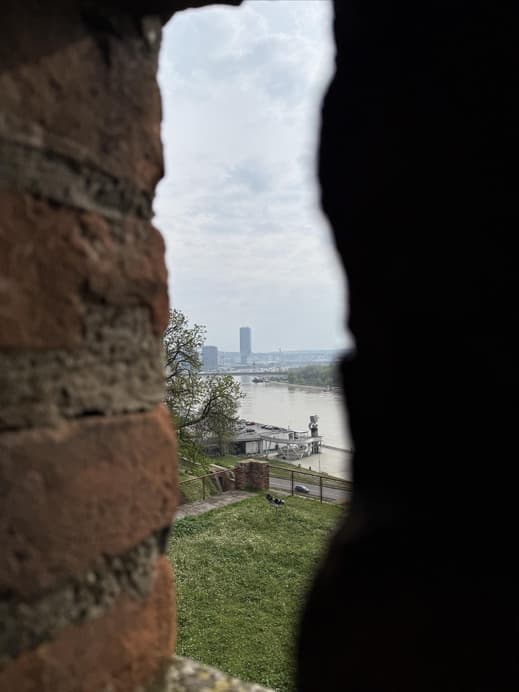 Ein Blick durch einen Mauerspalt auf einen Fluss und die Waterfront in Belgrad.