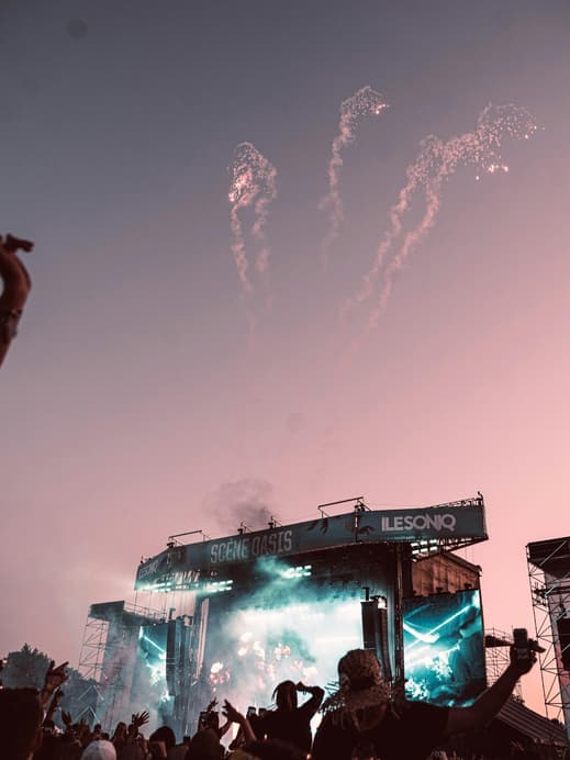 Festival-Bühne bei rosafarbener Dämmerung mit Feuerwerk am Himmel.