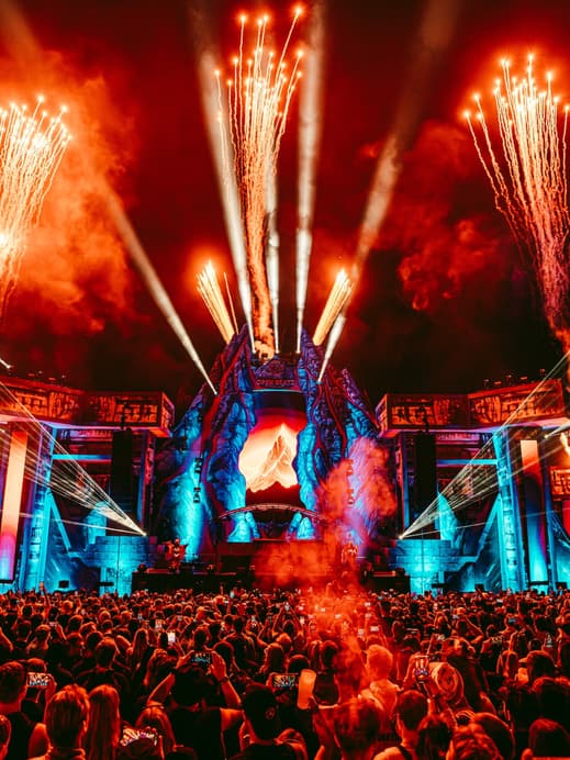 Eine Festivalbühne mit Feuerwerk und einer Menschenmenge davor.