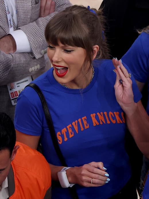 Taylor Swift mit einem blauen Shirt schreit euphorisch und schaut zur Seite nach links.