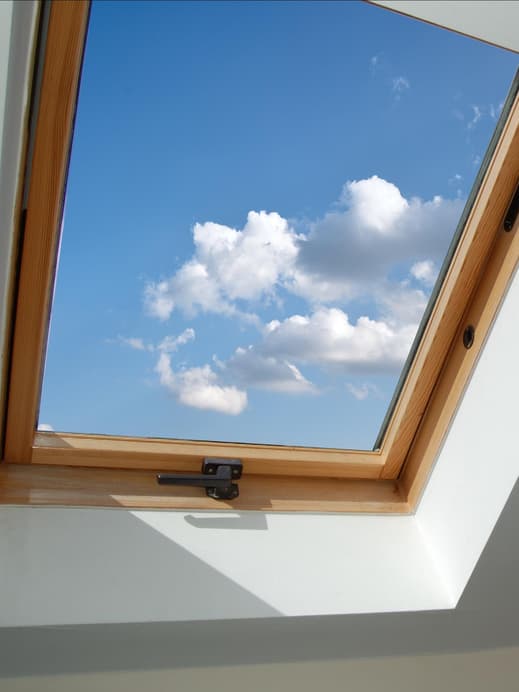 Dachgeschoss Fenster aus Holz mit Blick auf den blauen Himmel mit Wolken.