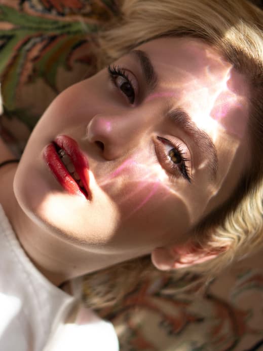 Frau mit glänzendem Lippenstift und Sonne im Gesicht