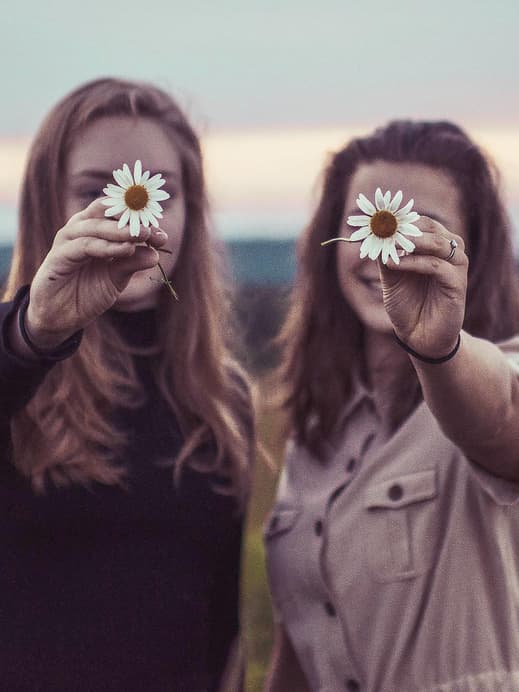 Zwei Frauen halten Blumen vor ihr Gesicht