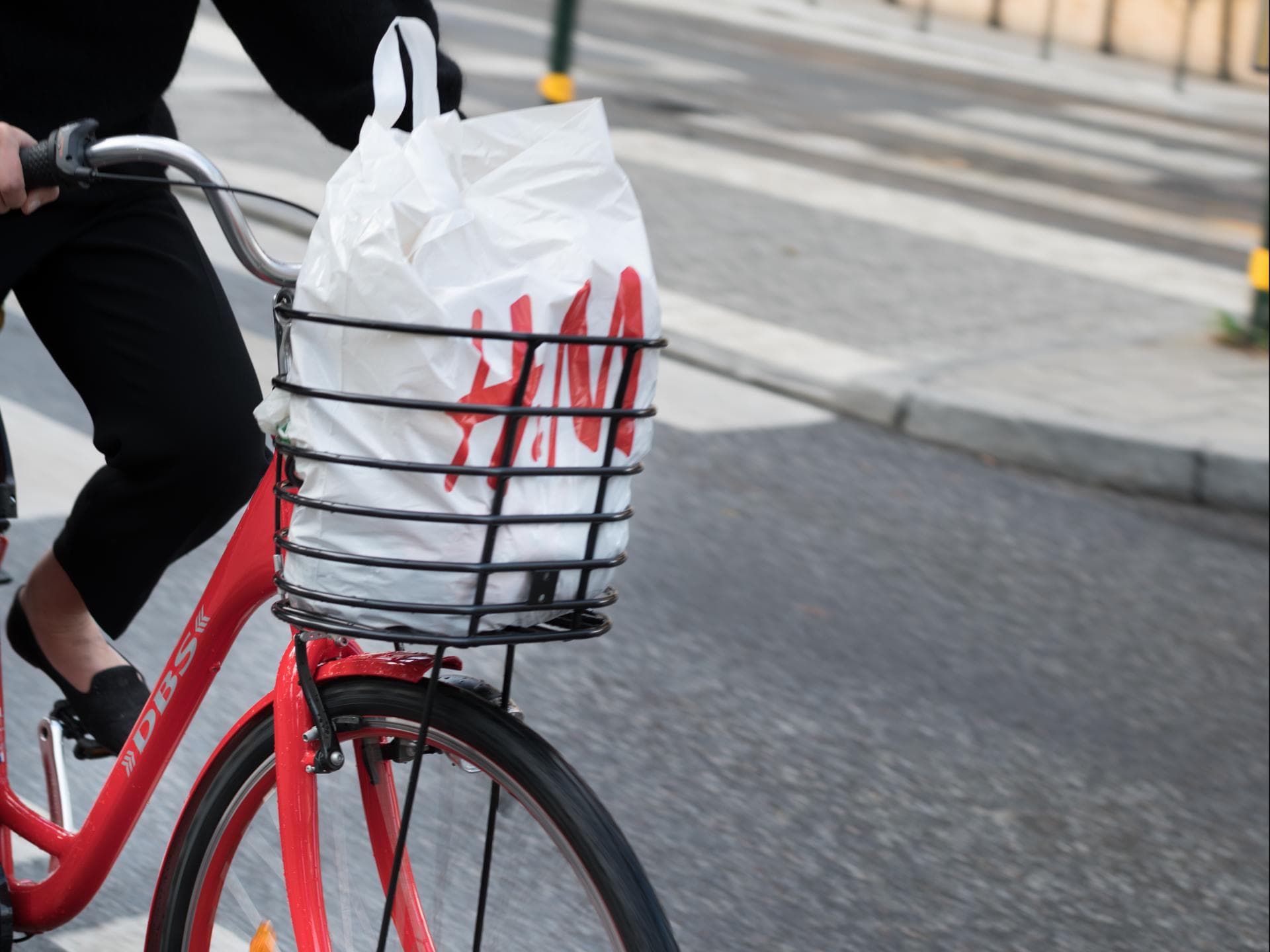 Rotes Fahrrad mit H&M-Tüte im Fahrradkorb auf Straße