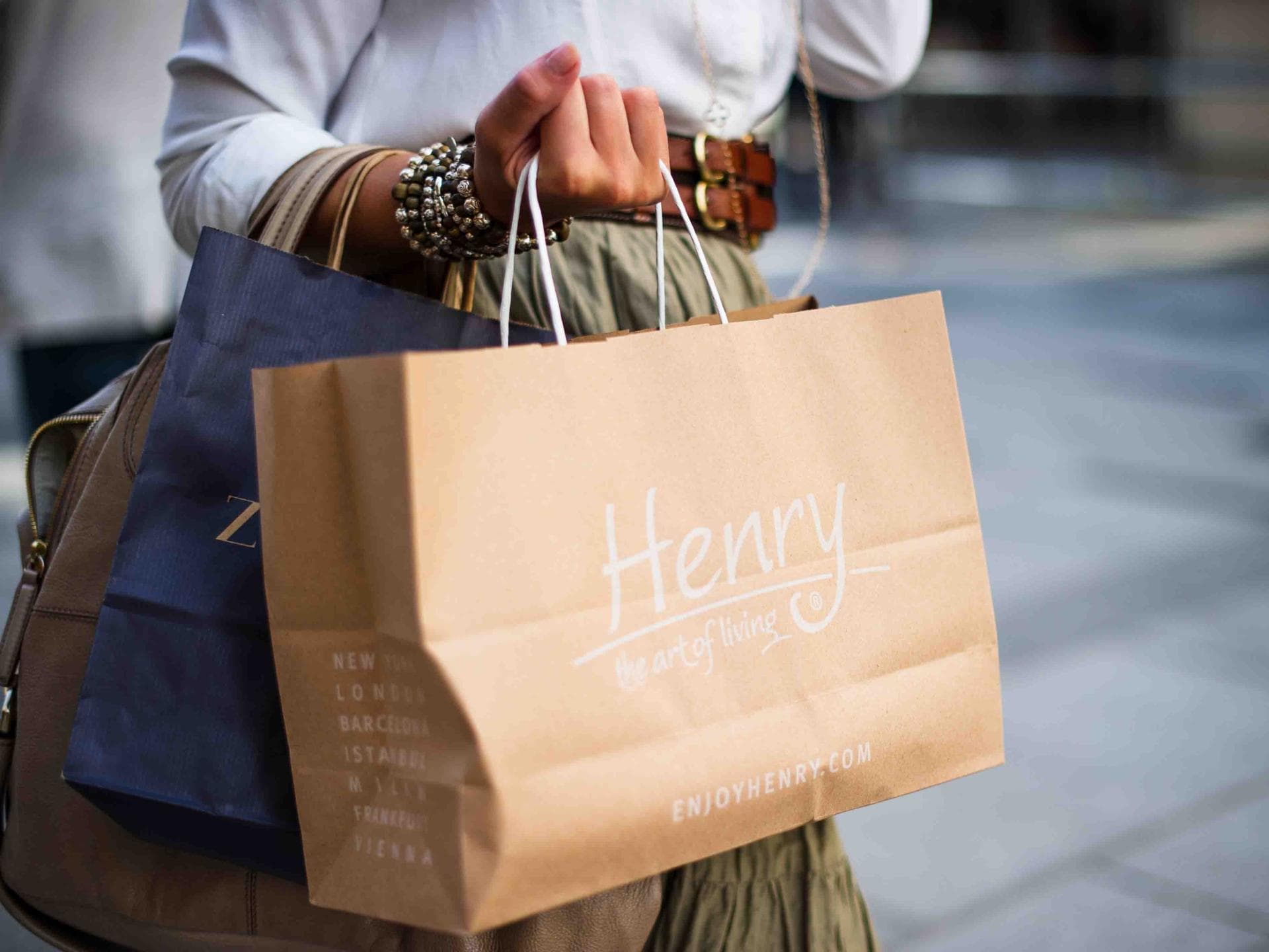 Muss man neue Kleidung vor dem ersten Tragen waschen? Frau mit zwei Tüten in der Hand beim Shoppen auf der Straße