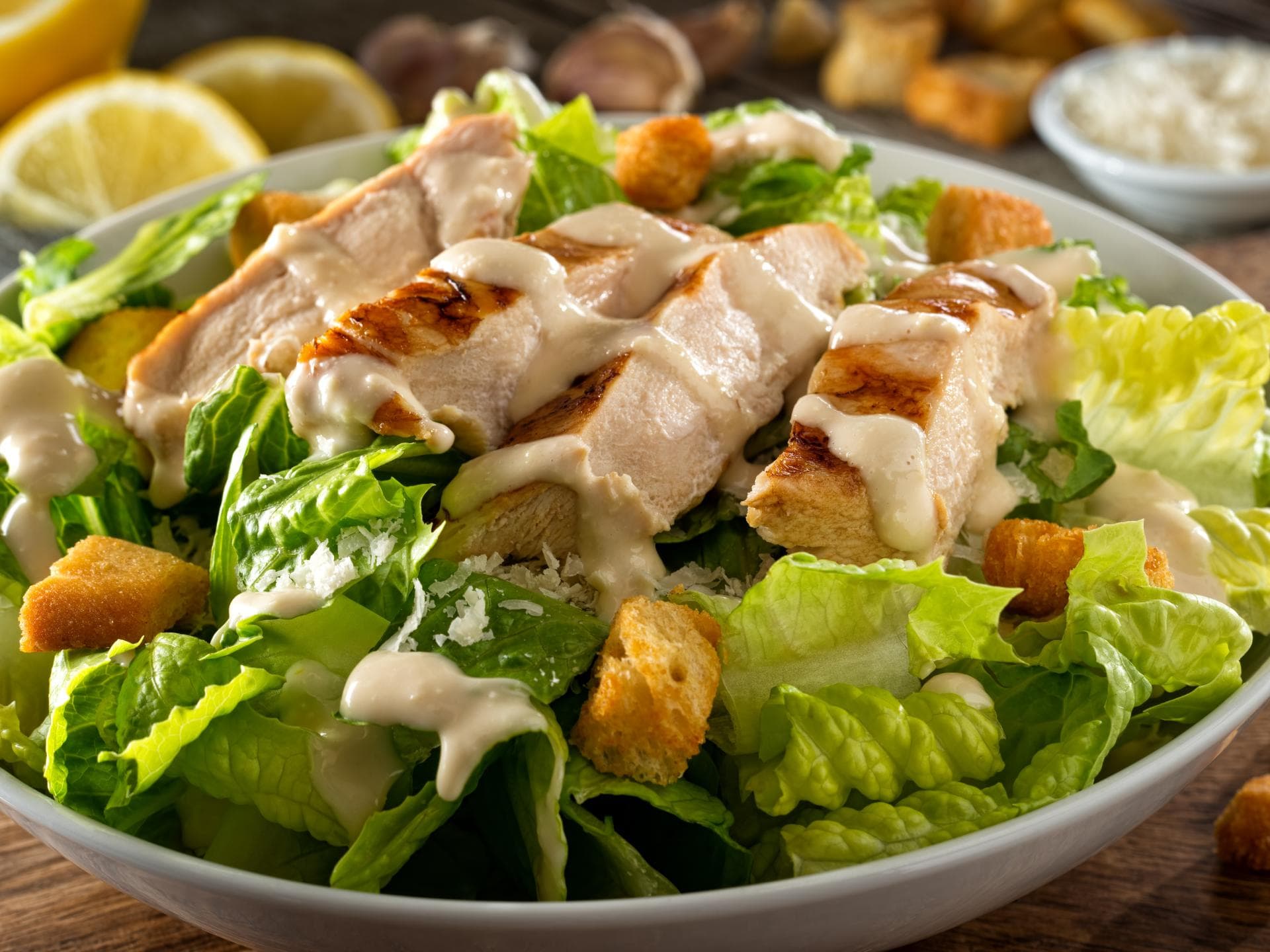 Grüner Salat mit Hähnchen, Dressing und Croutons in einer Schale