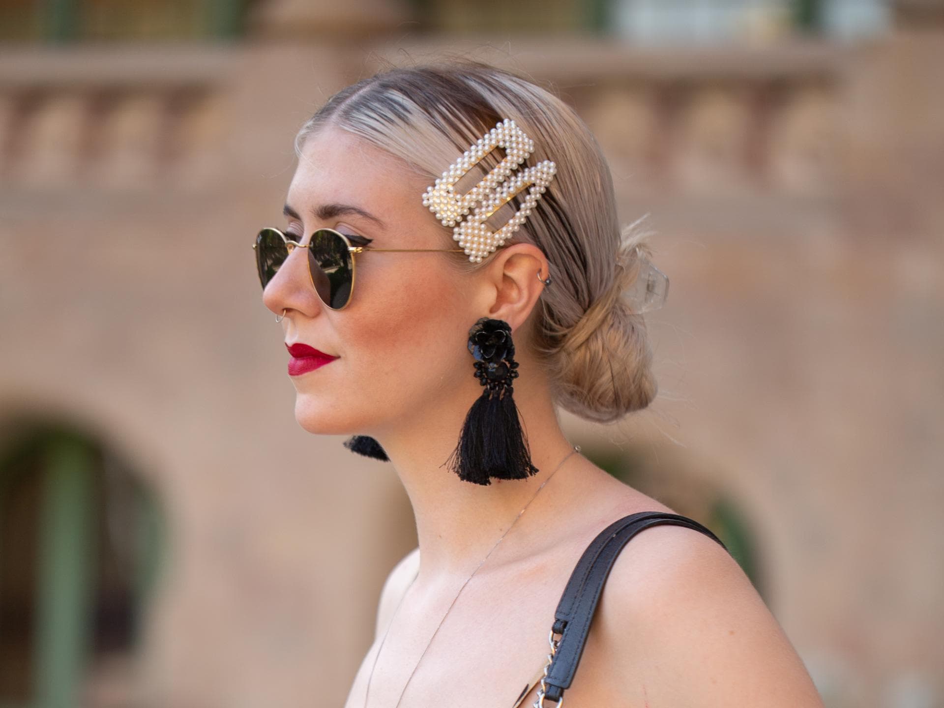 Blonde Frau mir Leo-Kleid, schwarzer Tasche und Haarspangen im Haar