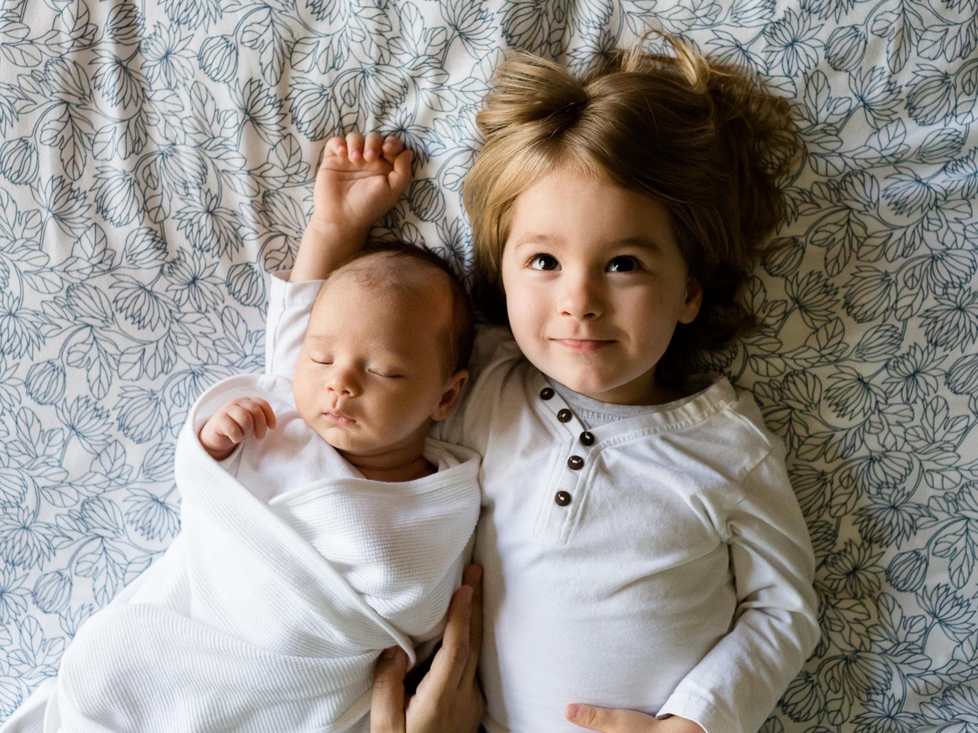 Ein Baby und ein Kleinkind liegen auf einem Bett