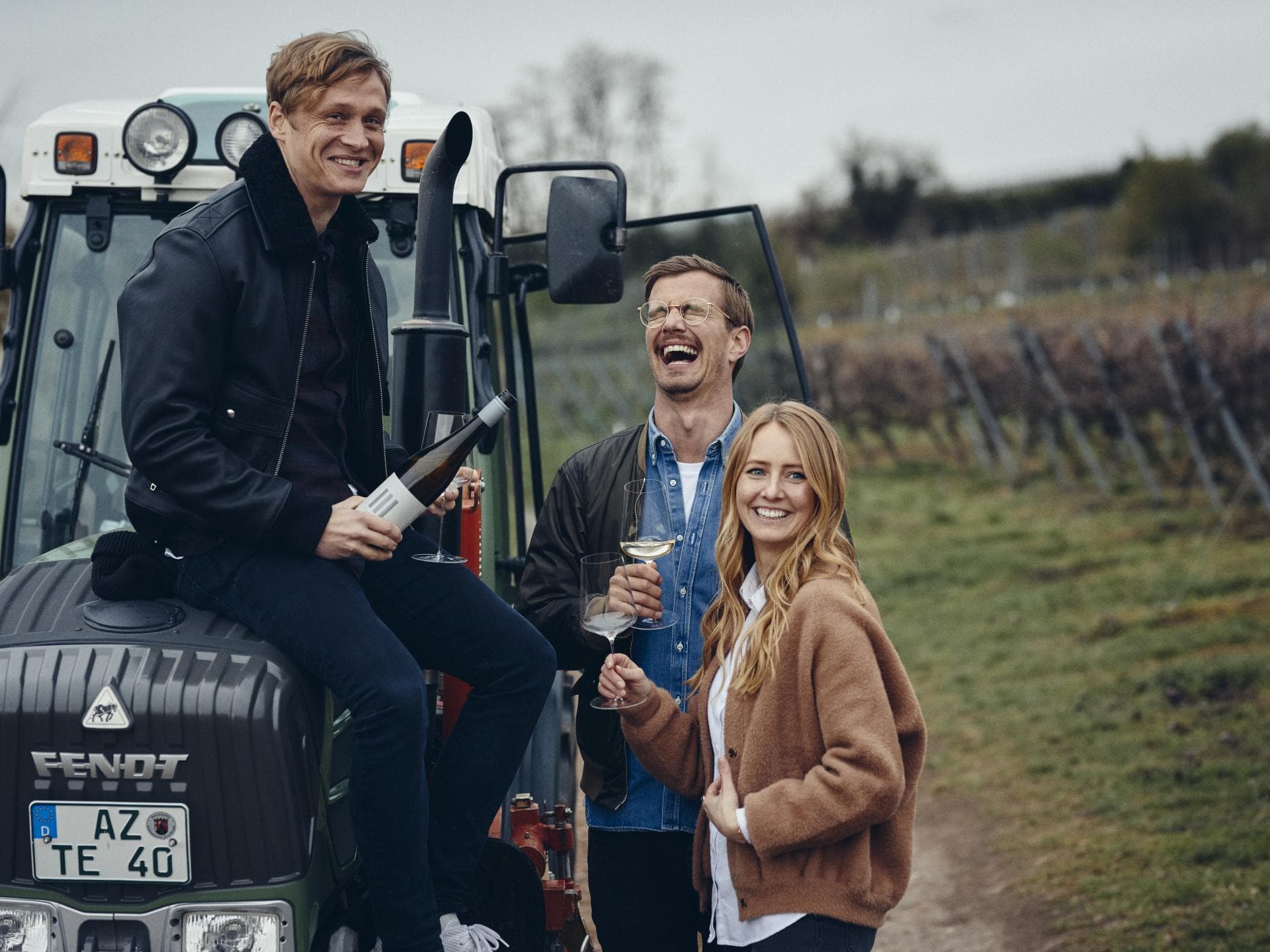 "3 Freunde"-Weine 3 Freunde sind mit Wein in der Hand auf einem Weinanbau-Gebiet