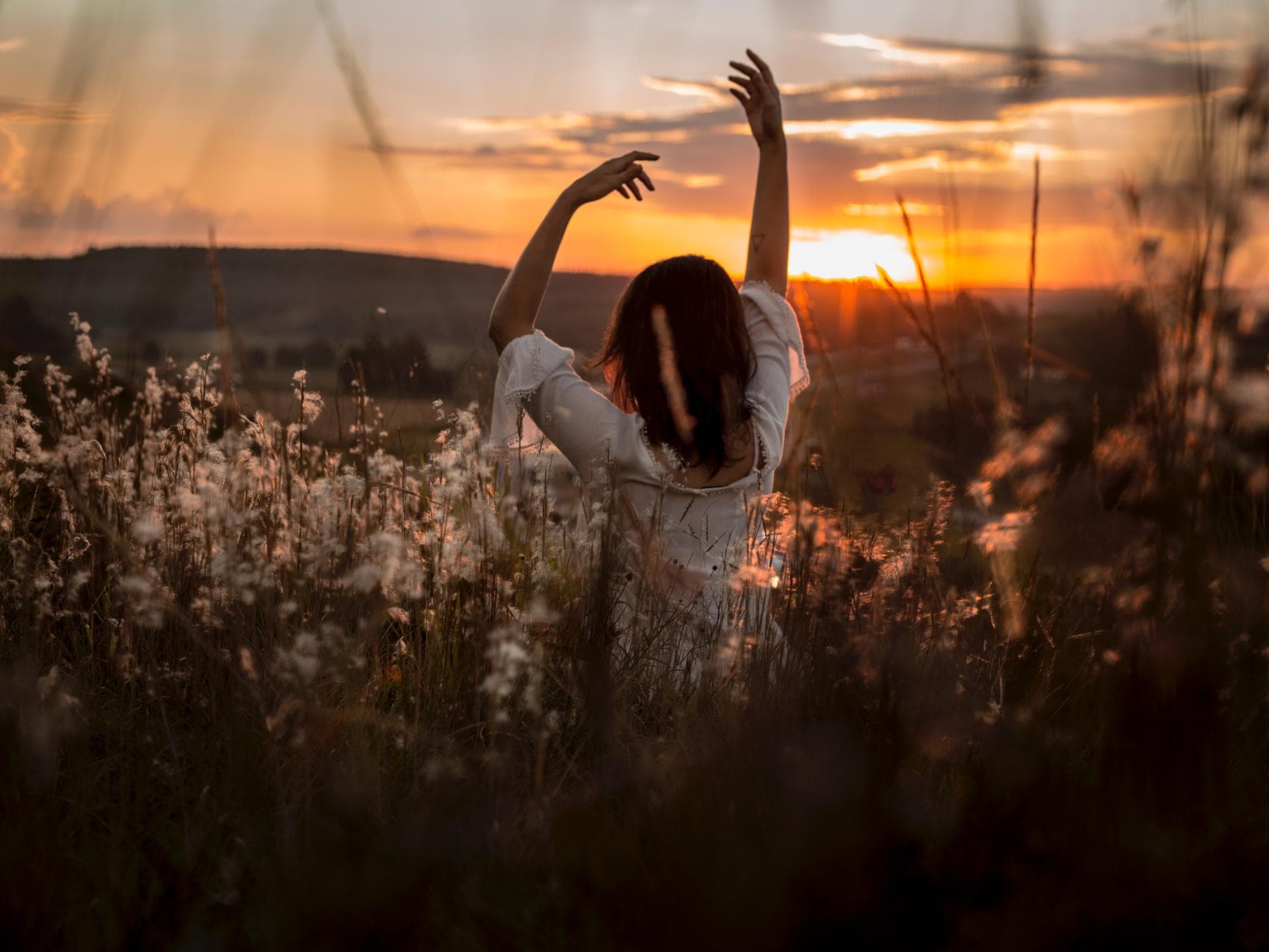 Horoskop Thema: Frau die im Feld steht und die Arme in die Luft streckt