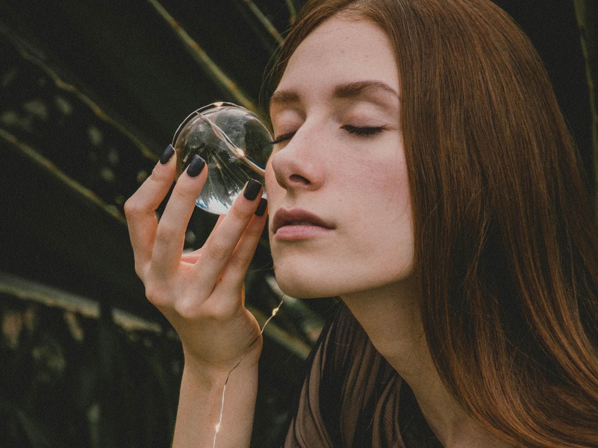 Horoskop Thema Horoskop: Frau hält sich Glaskugel an die Wange