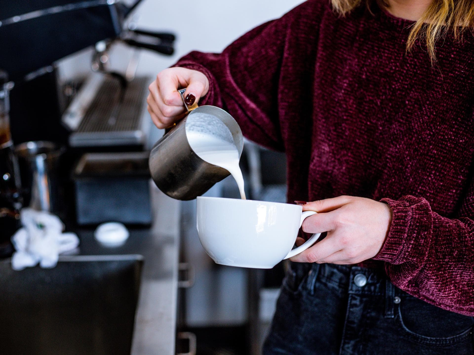 Frau gießt Milch in Tasse