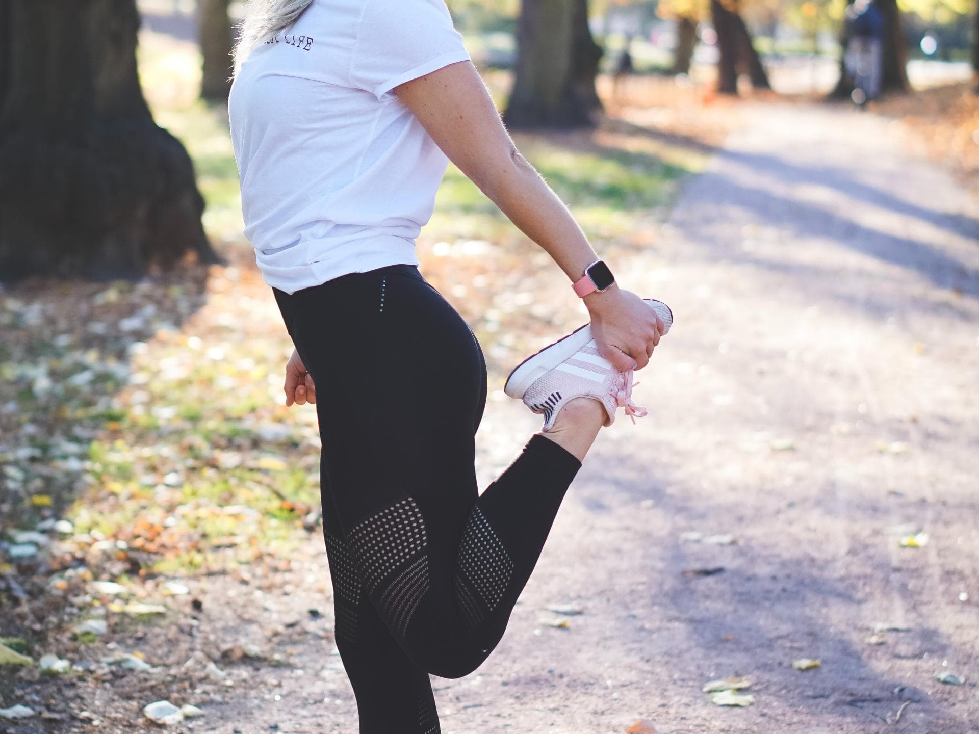 Fitbit: Diese neue Funktion für fast alle Geräte hat nicht mal die Apple Watch! Frau dehnt sich im Wald mit einer Fitbit am Handgelenk