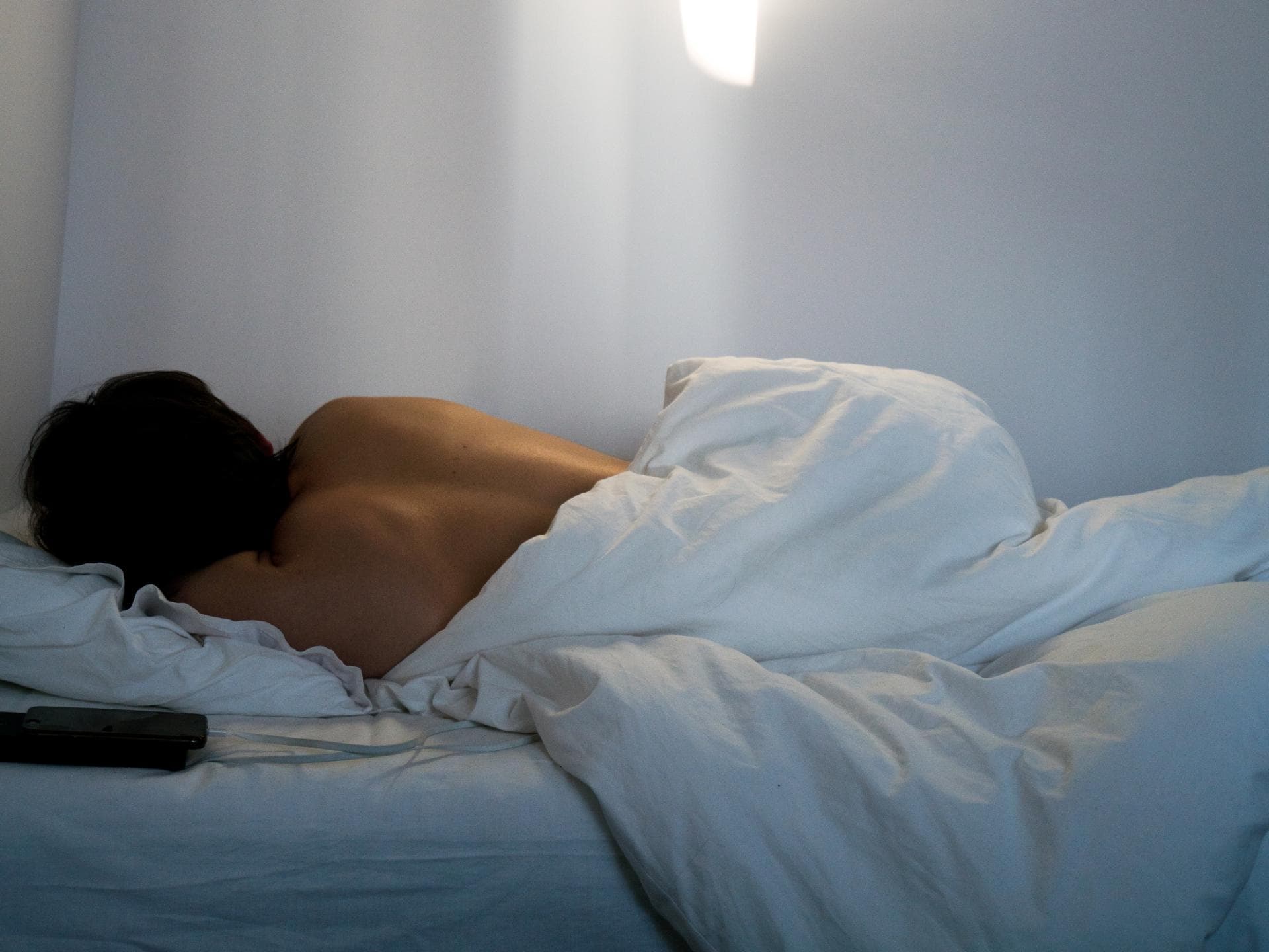 Einschlafen bei Hitze Rücken einer Frau die im Bett liegt