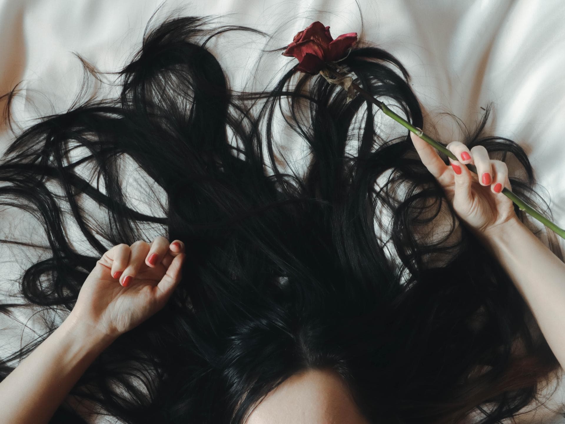 Sternzeichen Haarfarbe Frau mit schwarzen Haaren liegt auf dem Bett