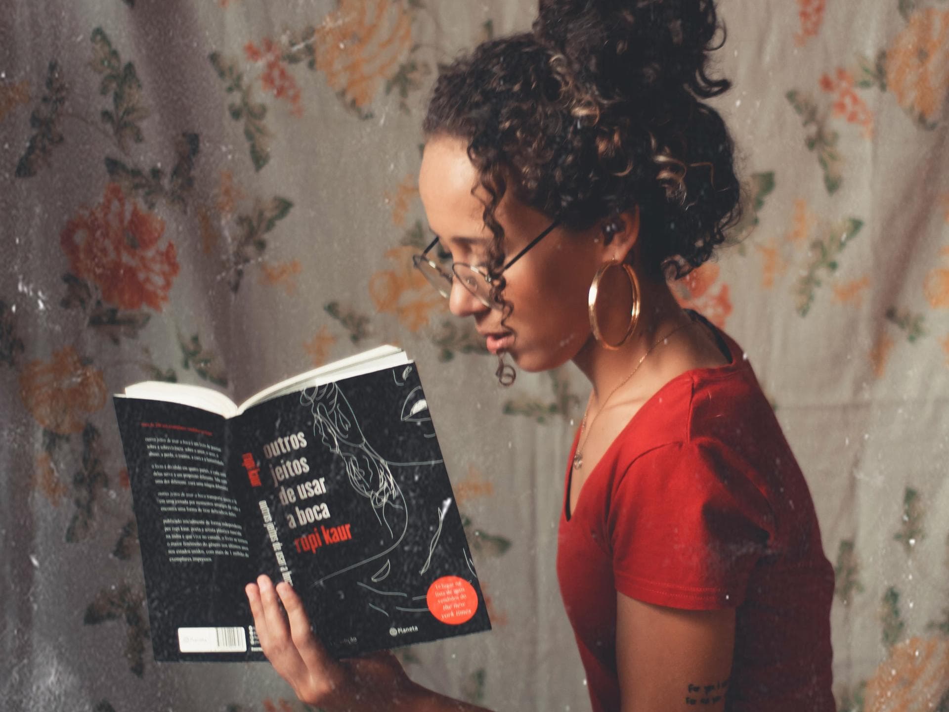 Buch Empfehlungen Mädchen mit Buch und Tasse in den Händen vor geblümter Wand