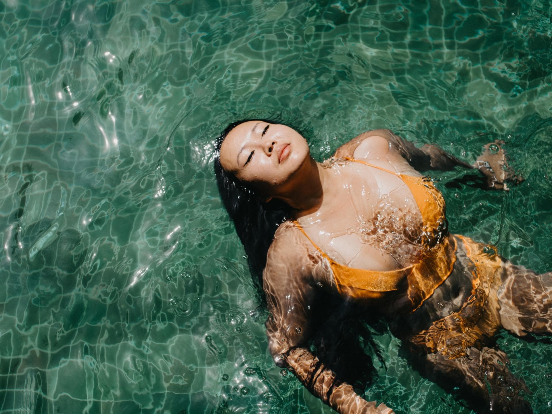 Monatshoroskop August Frau im gelben Bikini im Wasser
