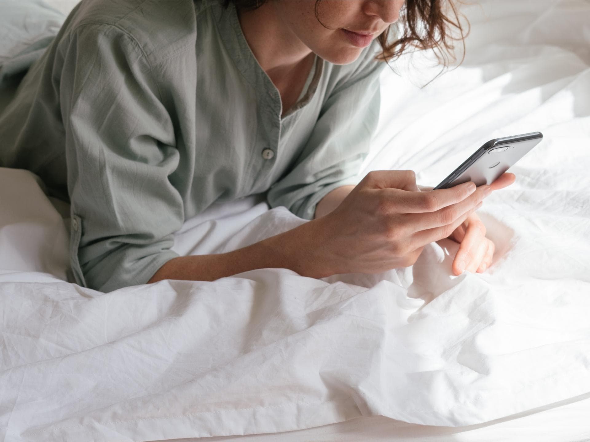 Fremdsprachen Apps Frau auf einem Bett mit Handy
