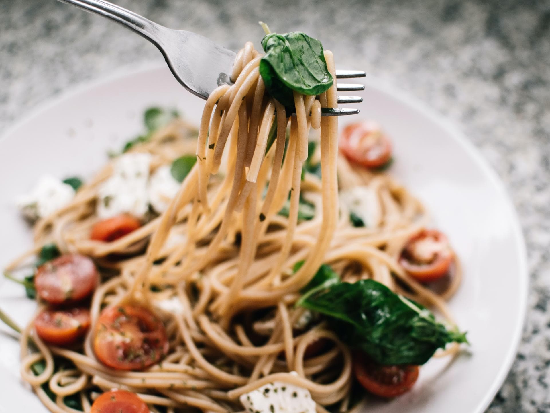Soul Food Weißer Teller mit Pasta, Tomaten und Spinat