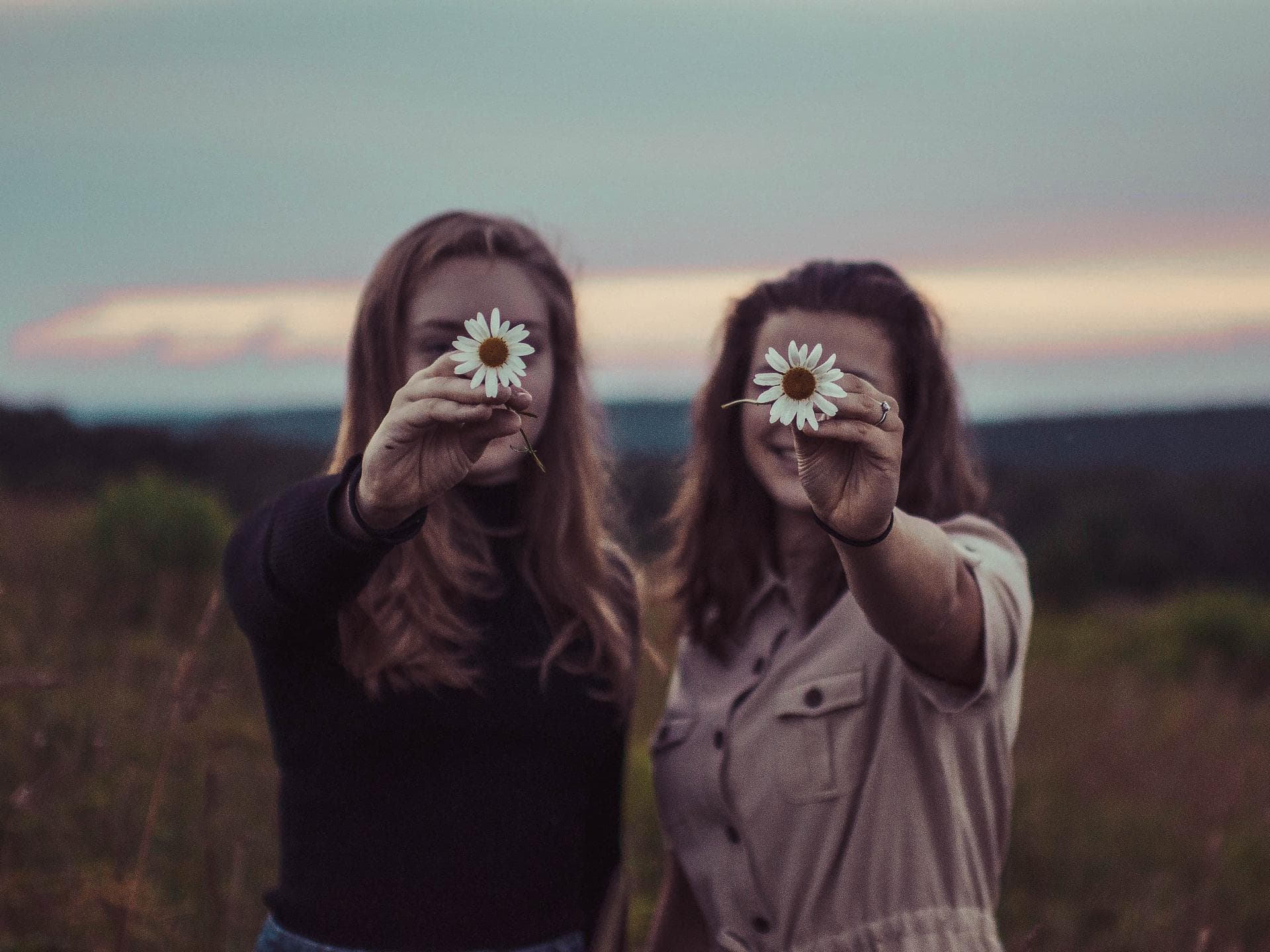 Zwei Frauen halten Blume in die Kamera