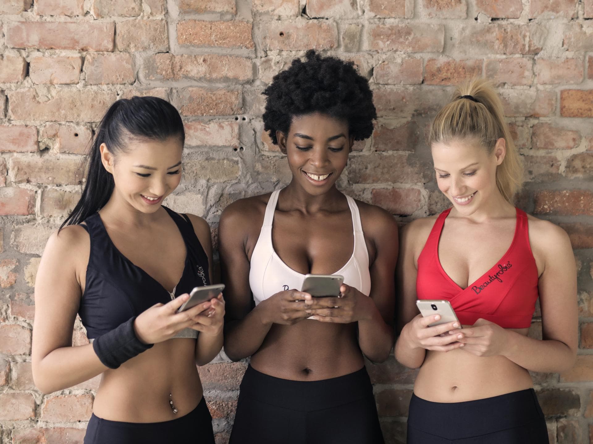Frauen in Sport-Outfit mit Handy in der Hand