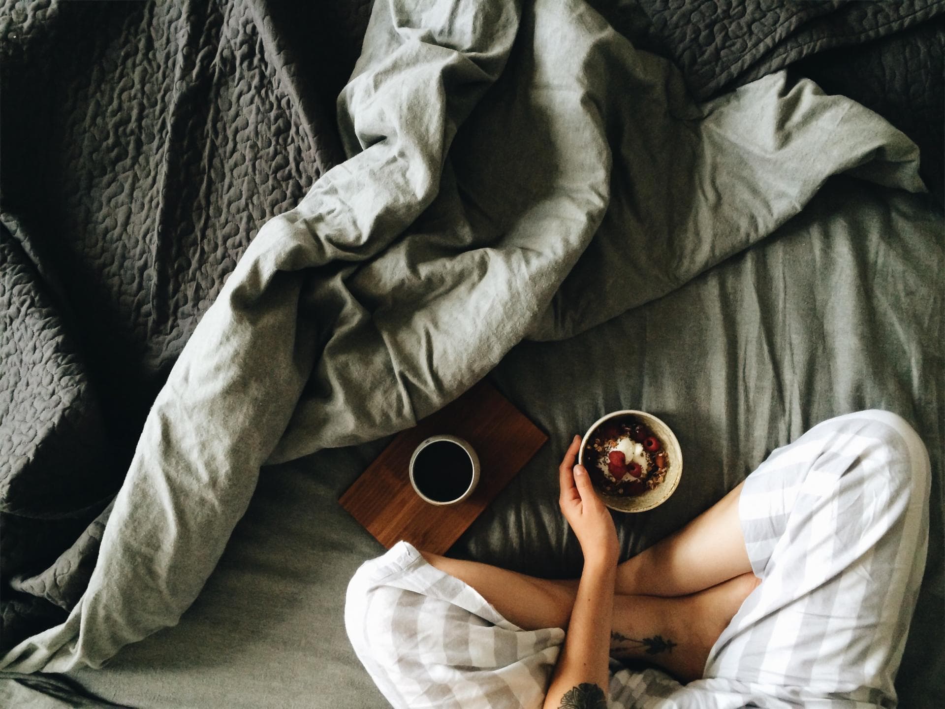 Frau sitzt mit Frühstück im Bett