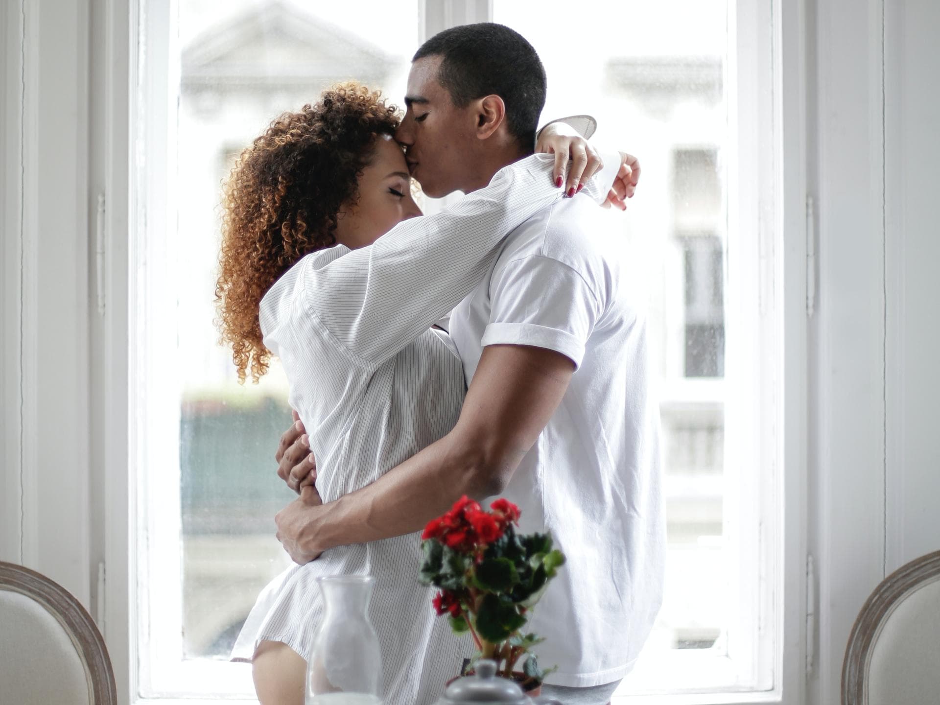 Diese Sternzeichen erleben ein Wochenende voll Liebe Frau und Mann umarmen sich vor einem Fenster