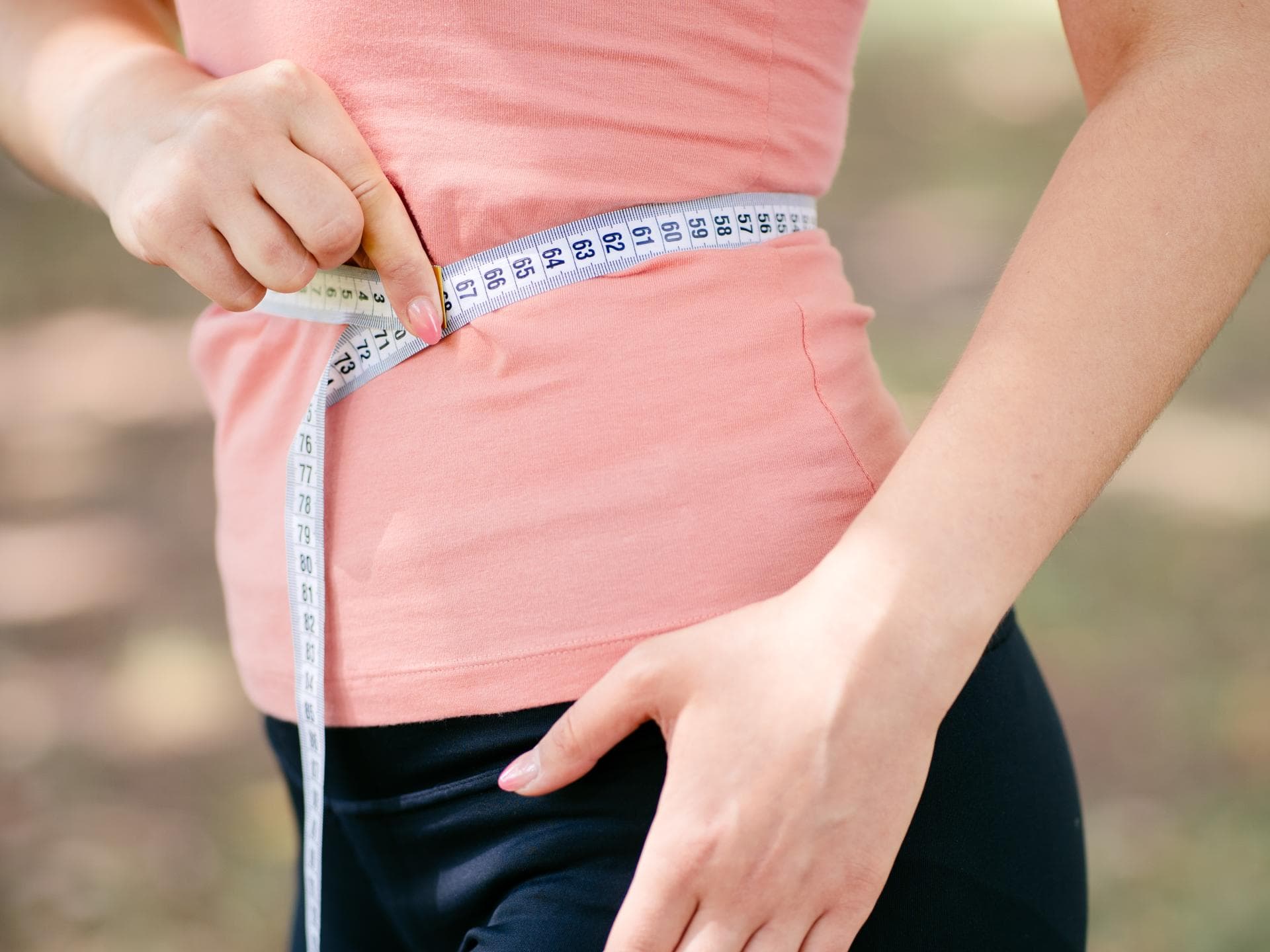 Frau hält Maßband an ihren Bauch