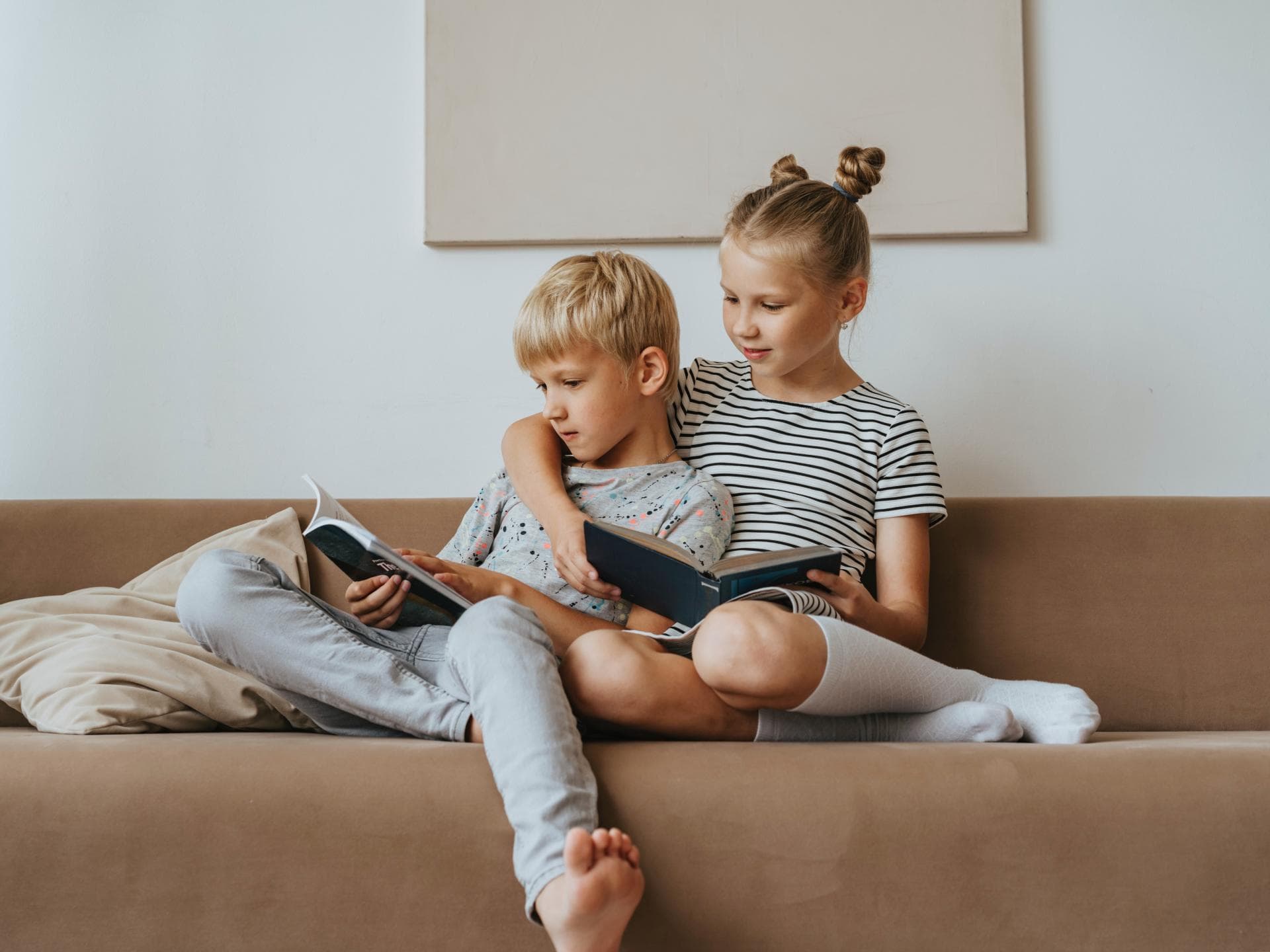 Große Schwester mit kleinem Bruder im Arm auf der Couch
