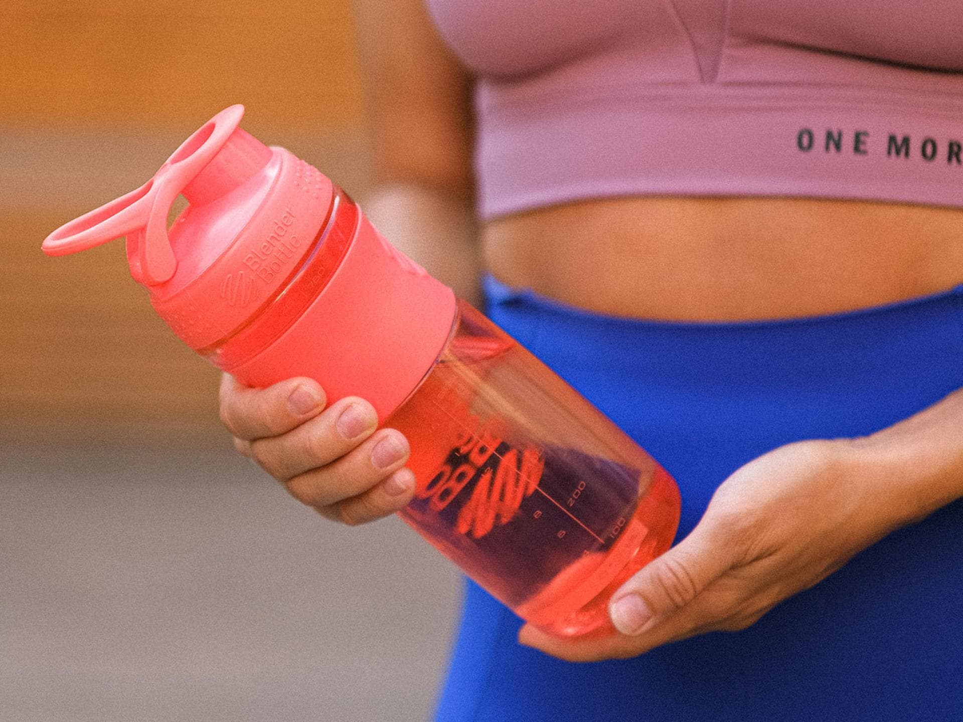 Frau im Sport-Outfit hält Flasche