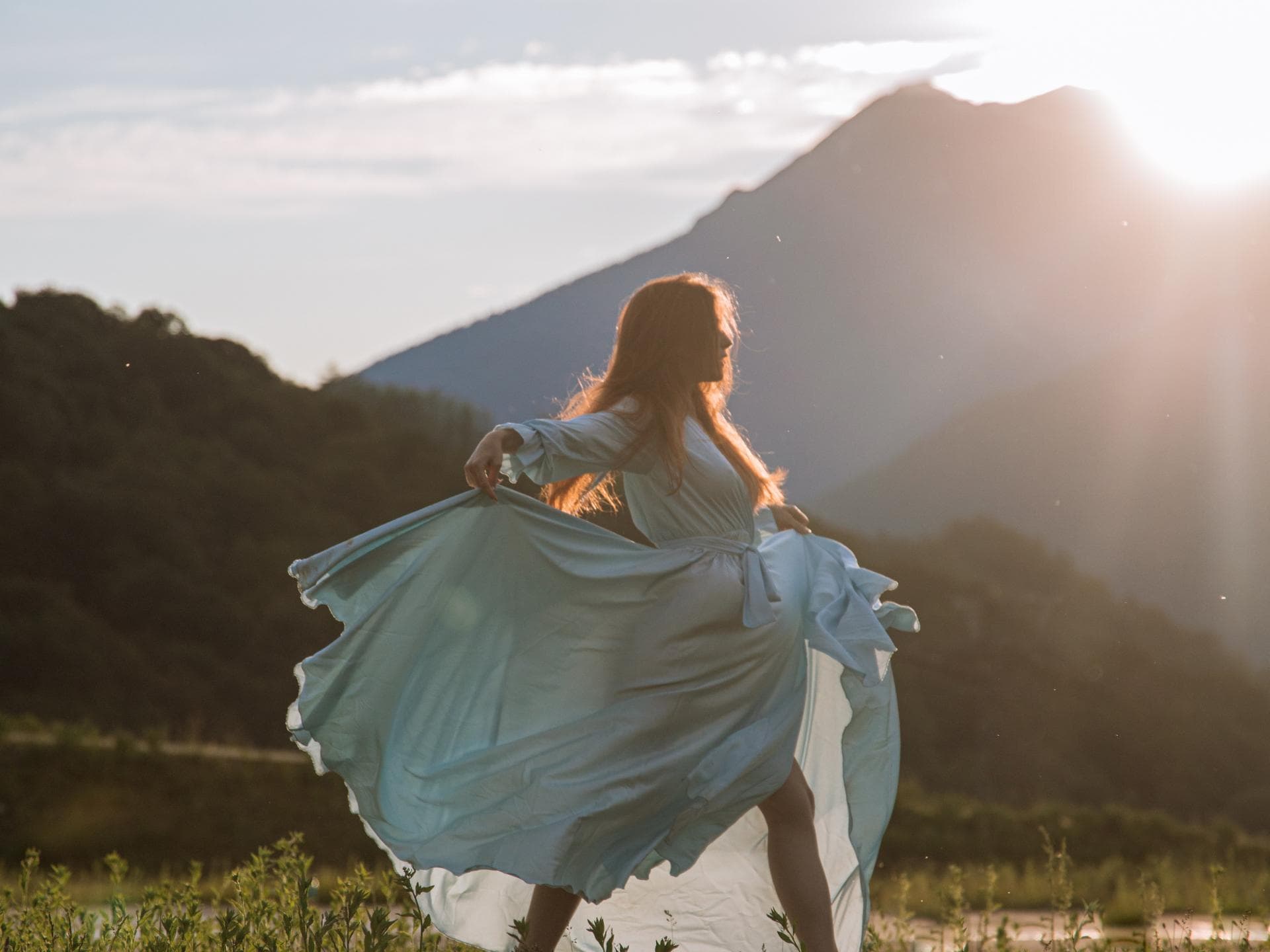 Frühlingsgefühle Frau tanzt im Kleid auf der Wiese bei Sonnenschein