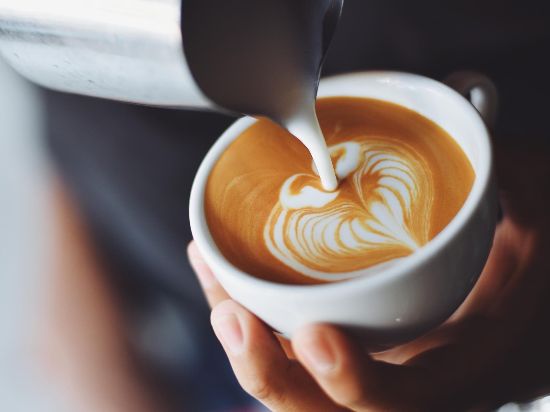 Milchschaum wird in Tasse gegossen