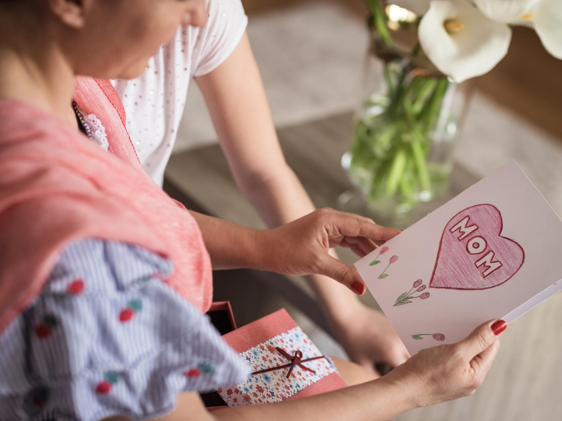 Muttertagssprüche: Frau hält eine Karte in der Hand auf der "Mom" steht