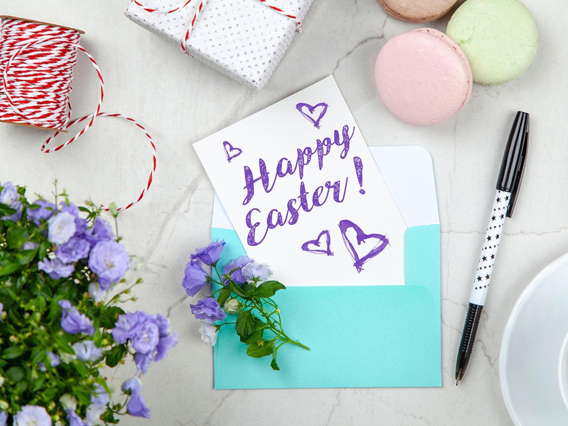 Osterkarte im Umschlag mit Macarons, Geschenken und Blumen
