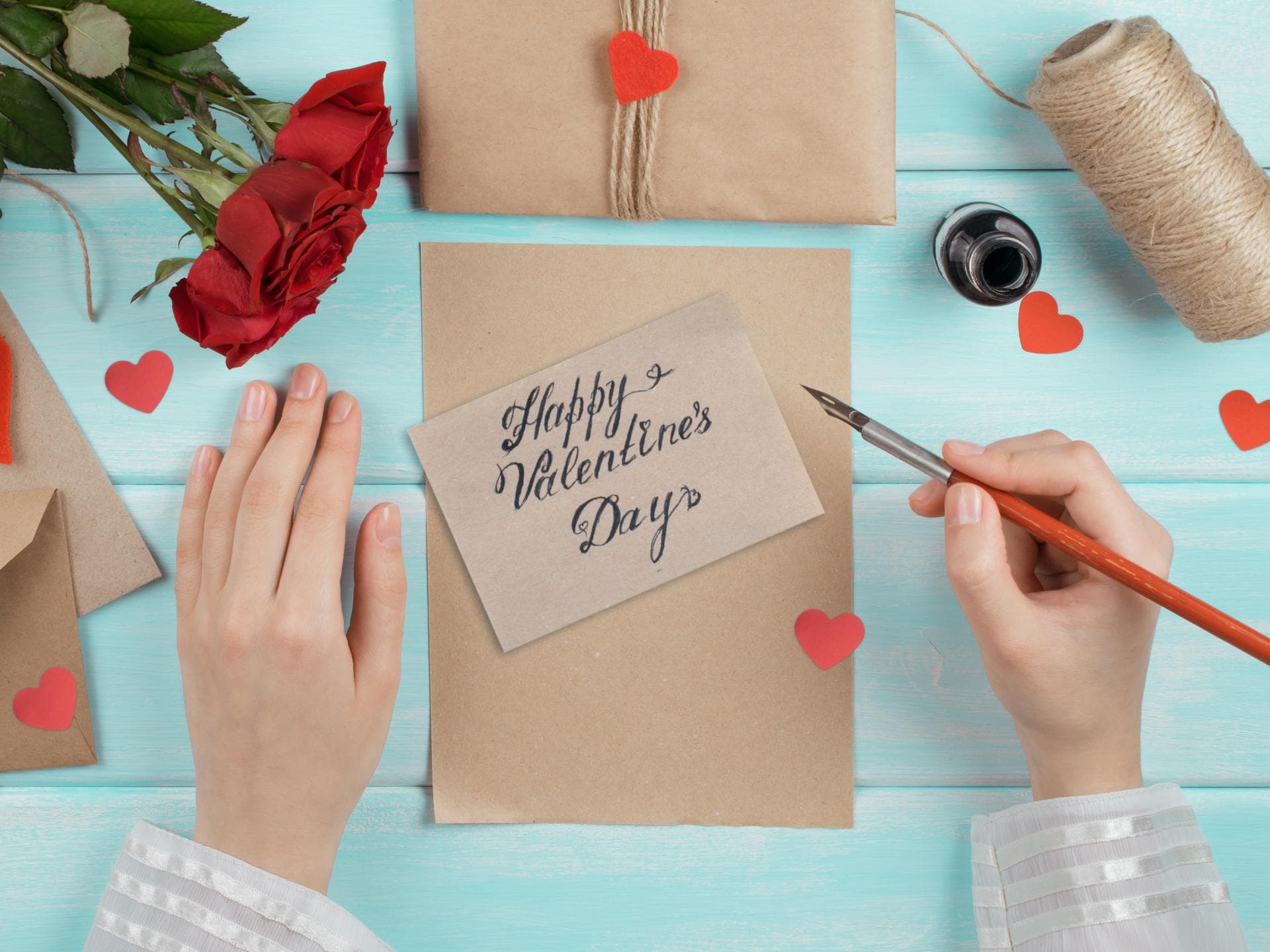 Valentinstag Sprüche: Zwei Hände schreiben eine Valentinstag Karte