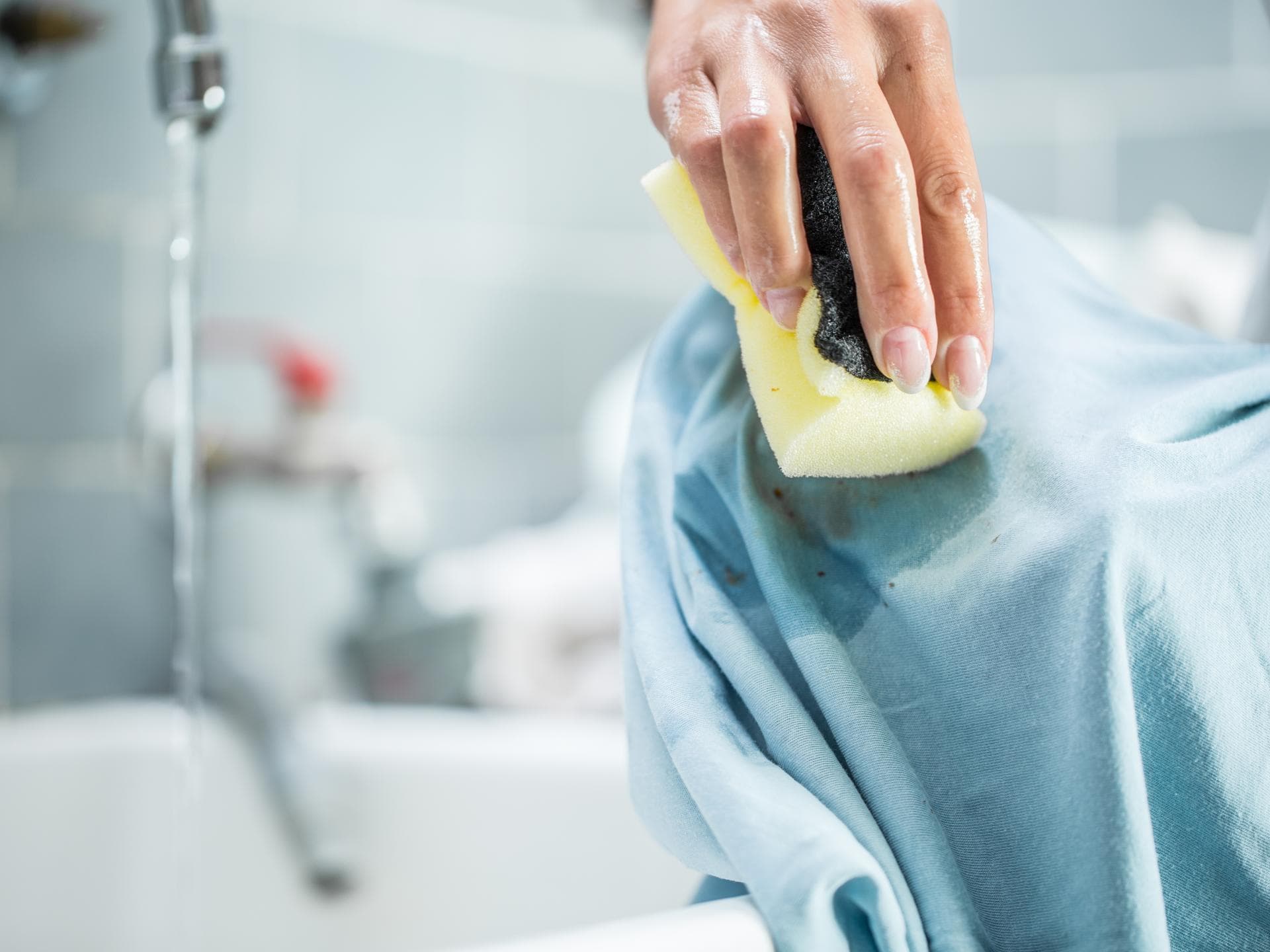 Fettflecken entfernen: Mit diesen Hausmitteln knappt's Fettflecken entfernen: Hand wäscht Fleck mit Schwamm aus Kleidungsstück
