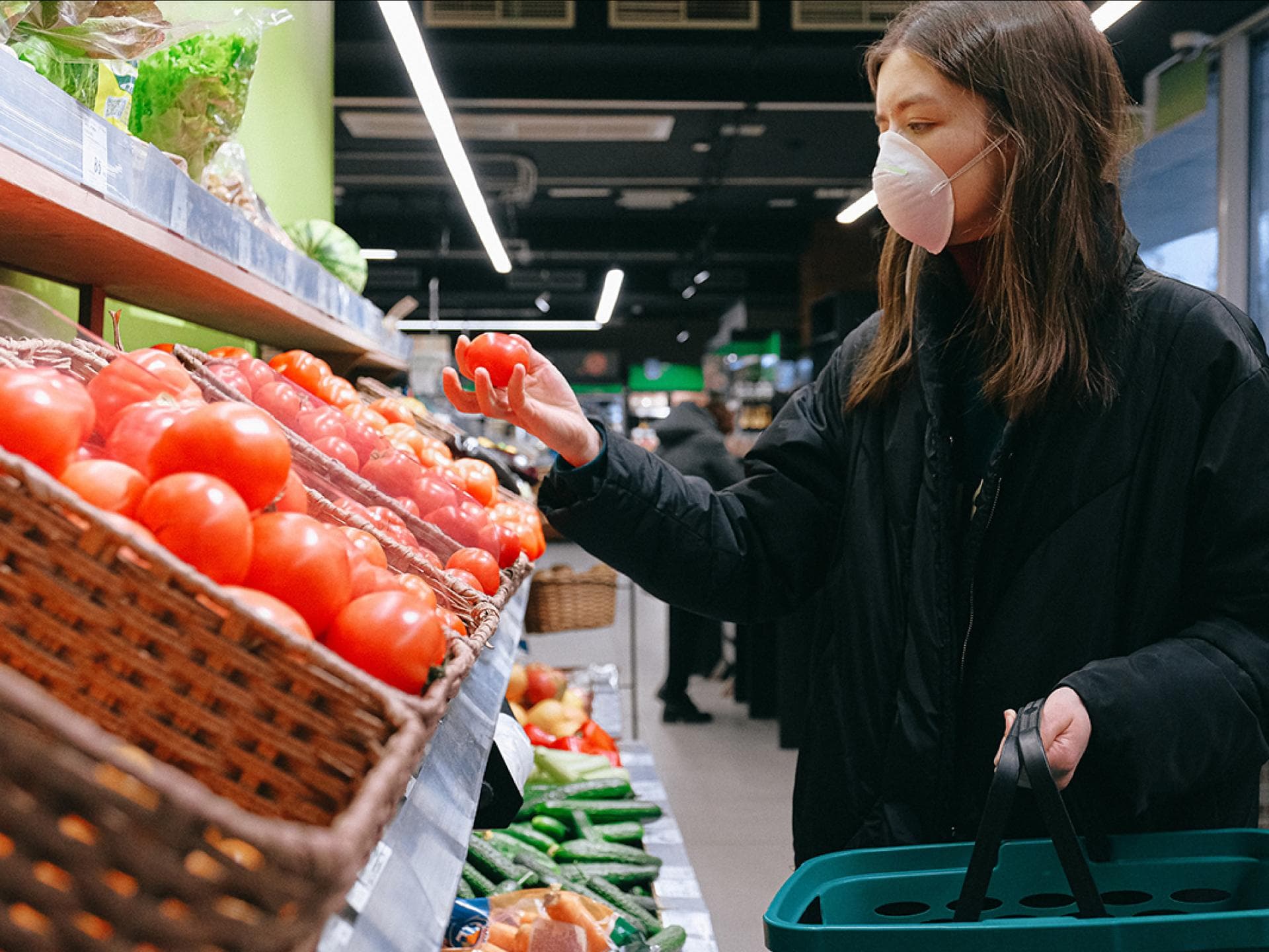 Frau haelt Tomate im Supermarkt Frau haelt Tomate im Supermarkt