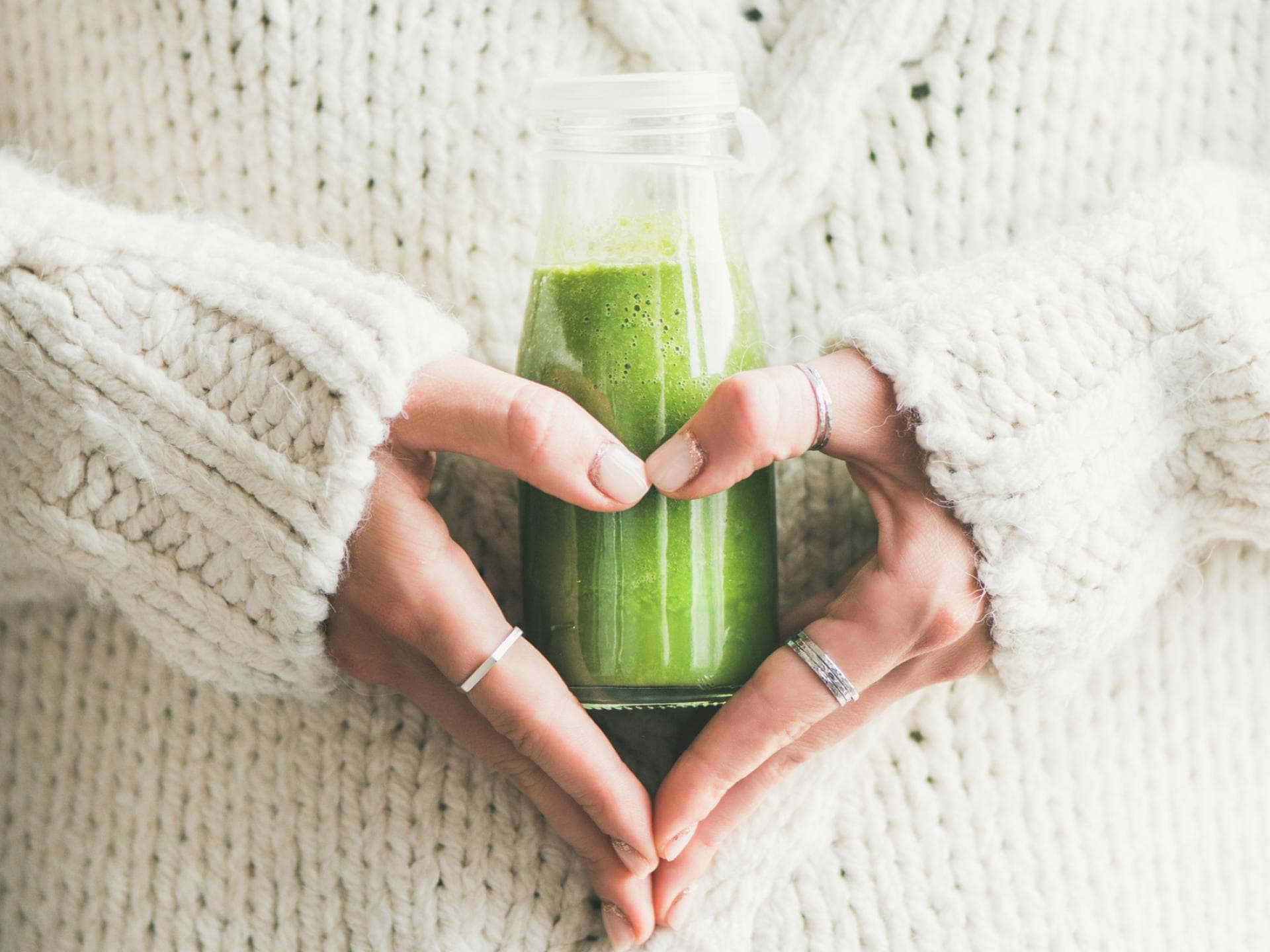 Frau hält einen grünen Smoothie in der Hand