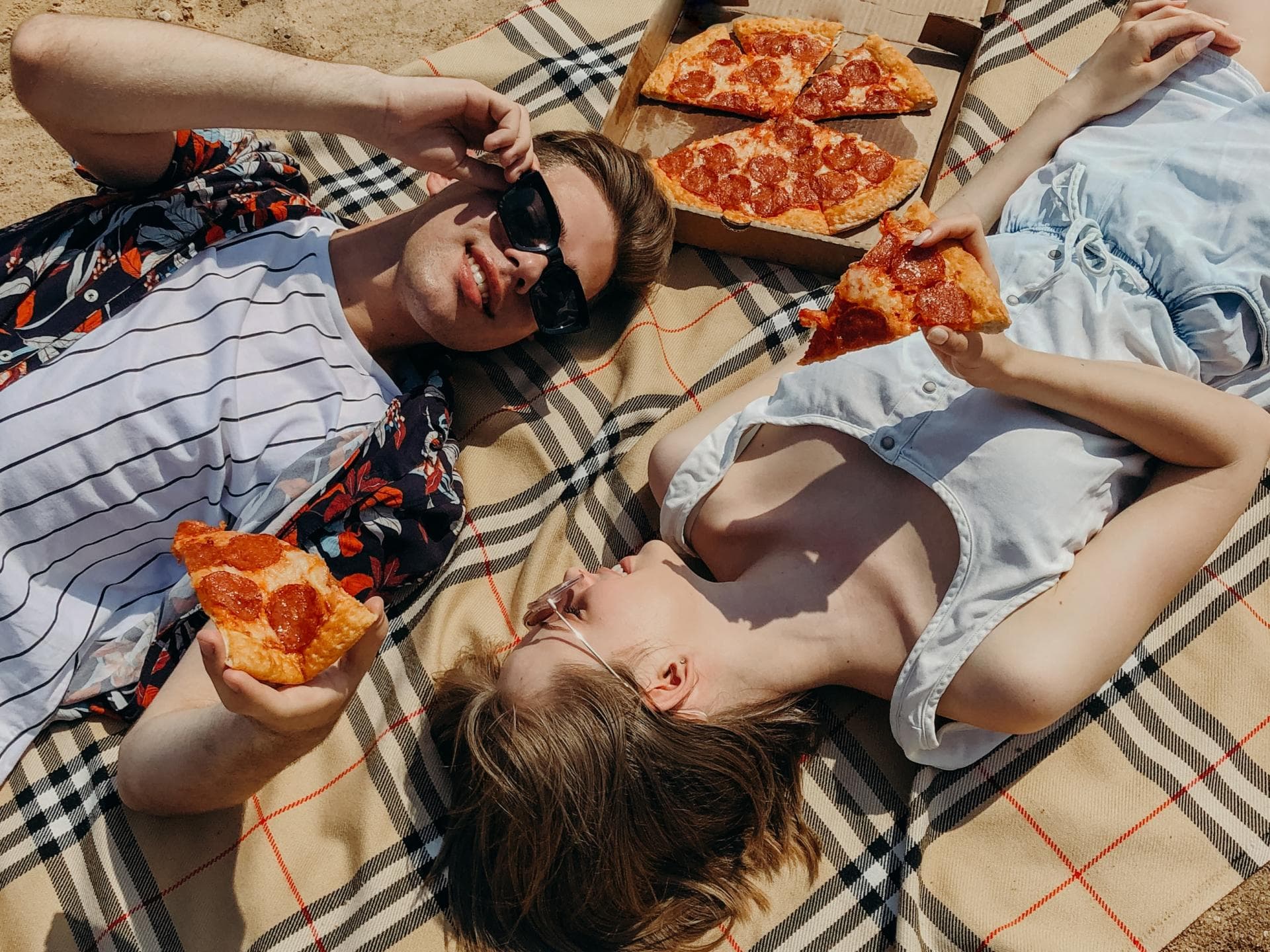 Horoskop: Diese Sternzeichen haben jetzt Glück in der Liebe Horoskop: Mann und Frau liegen auf Decke mit Pizza
