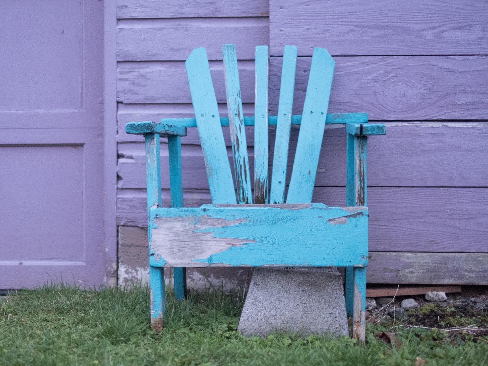 Gartenmöbel pflegen: Blauer Stuhl vor lila Wand