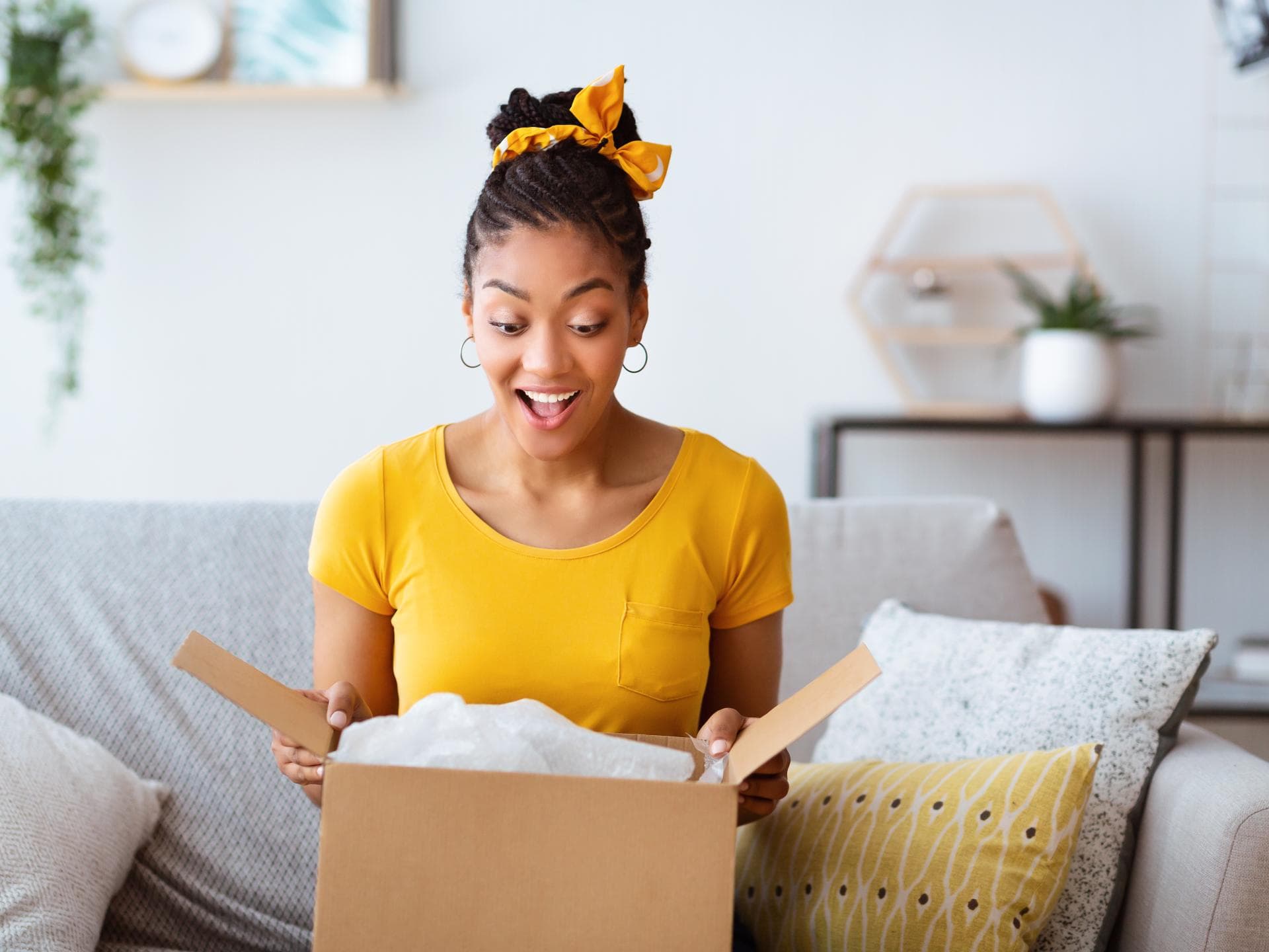 Frau im gelben T-Shirt öffnet Paket Frau im gelben T-Shirt öffnet Paket
