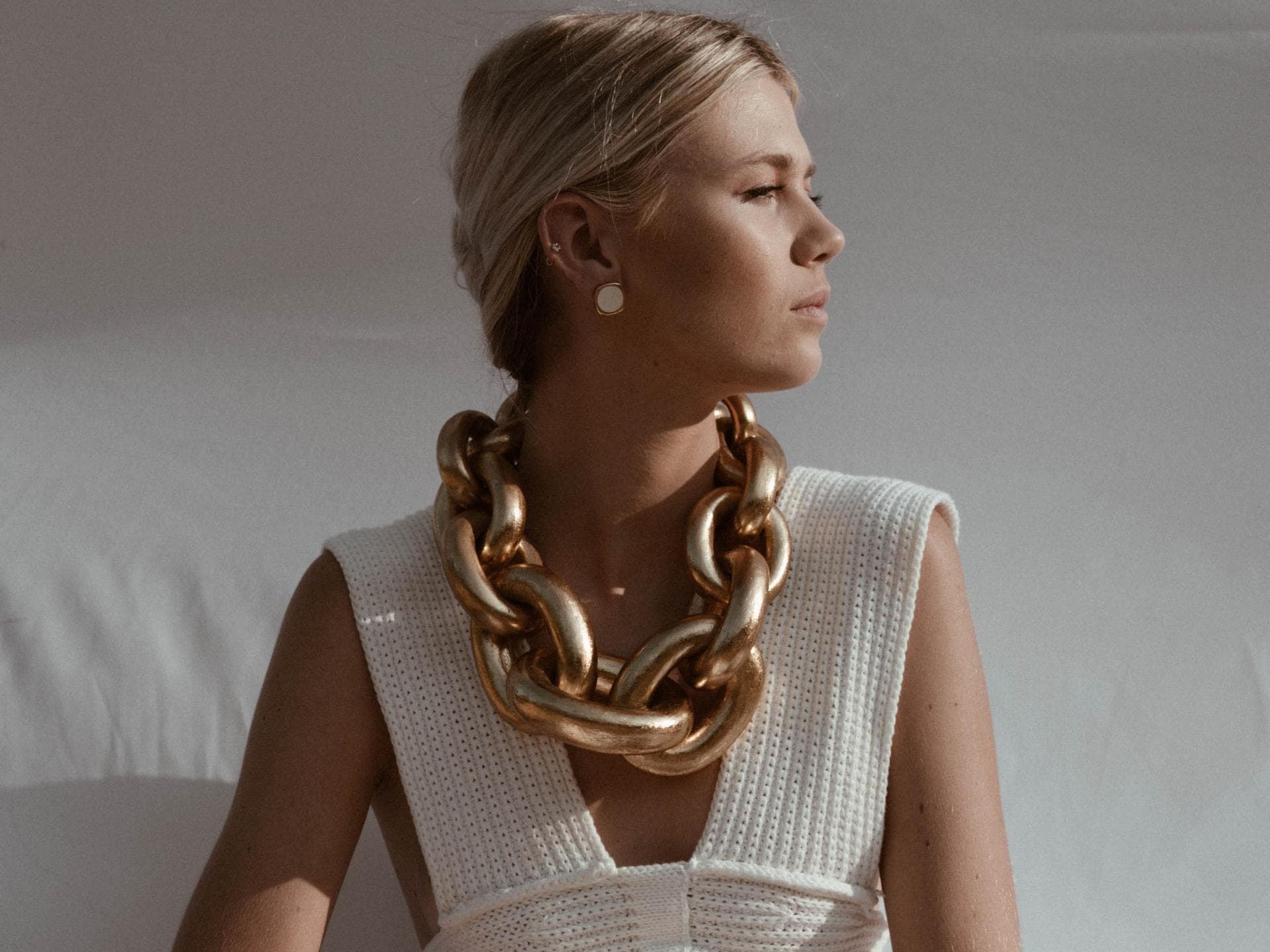 Horoskop: Frau mit weißem Outfit und Goldkette