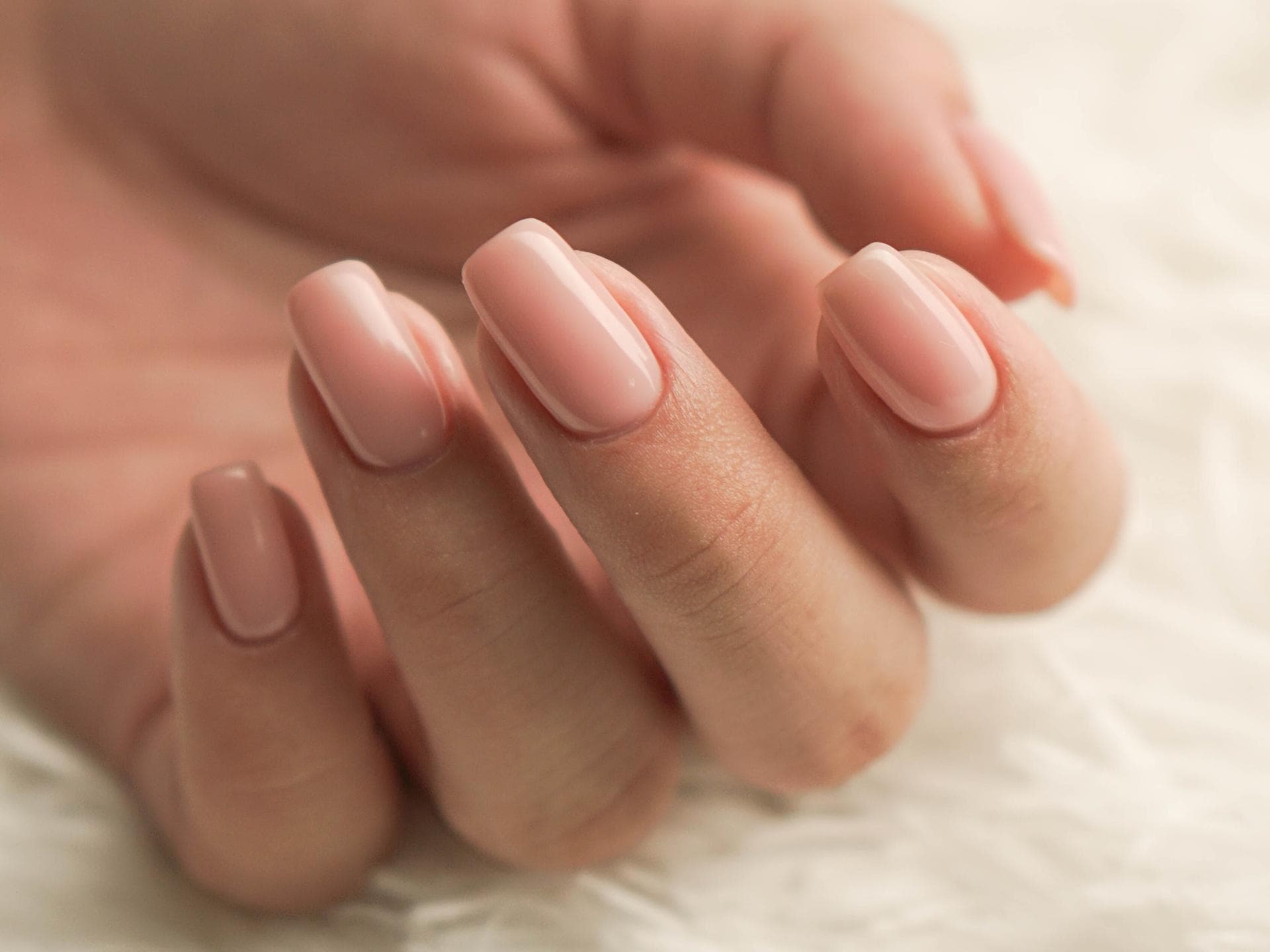 Hand mit natürlichen Gelnägeln