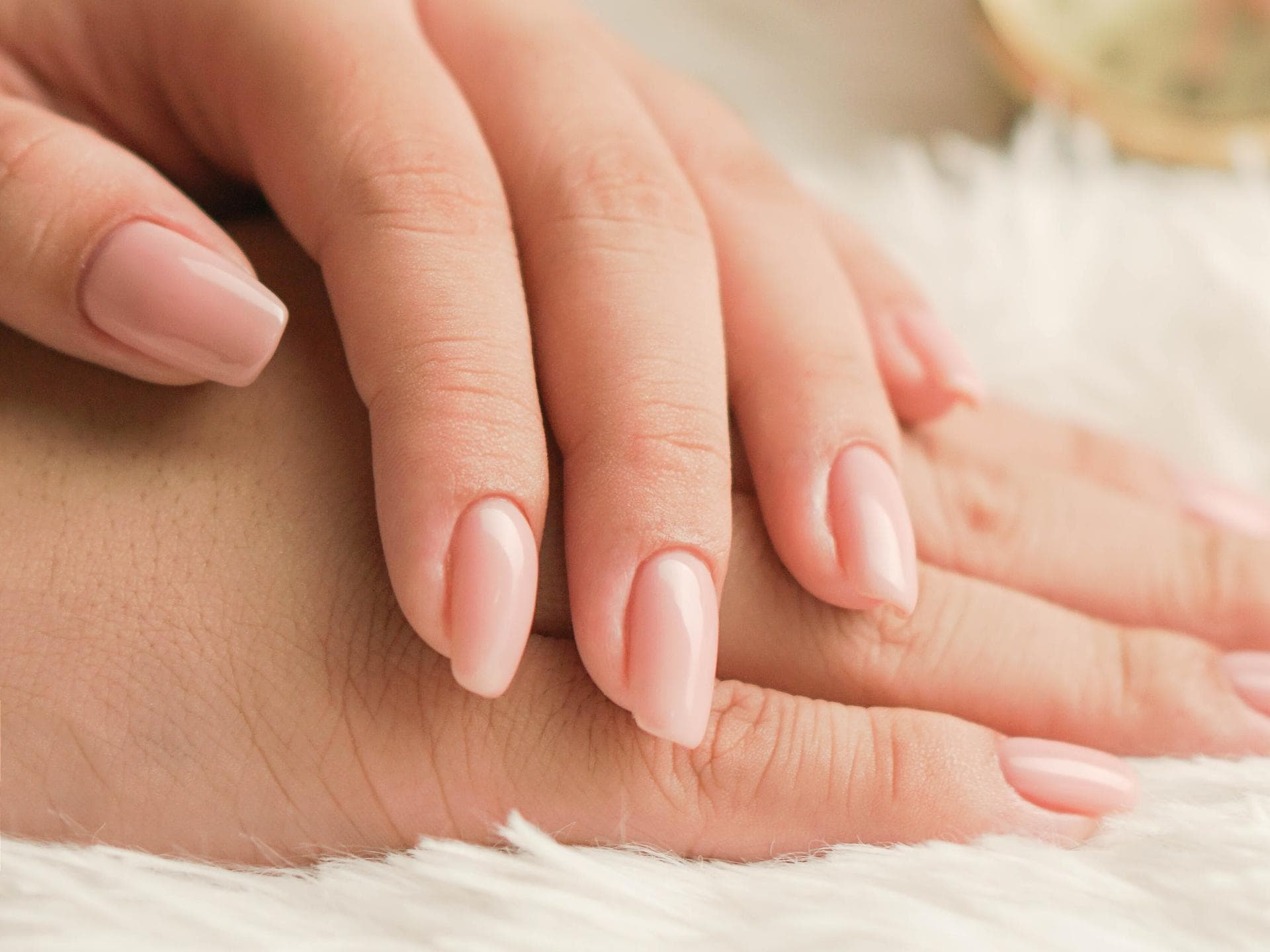 Hand mit natürlichen Gelnägeln in rosa