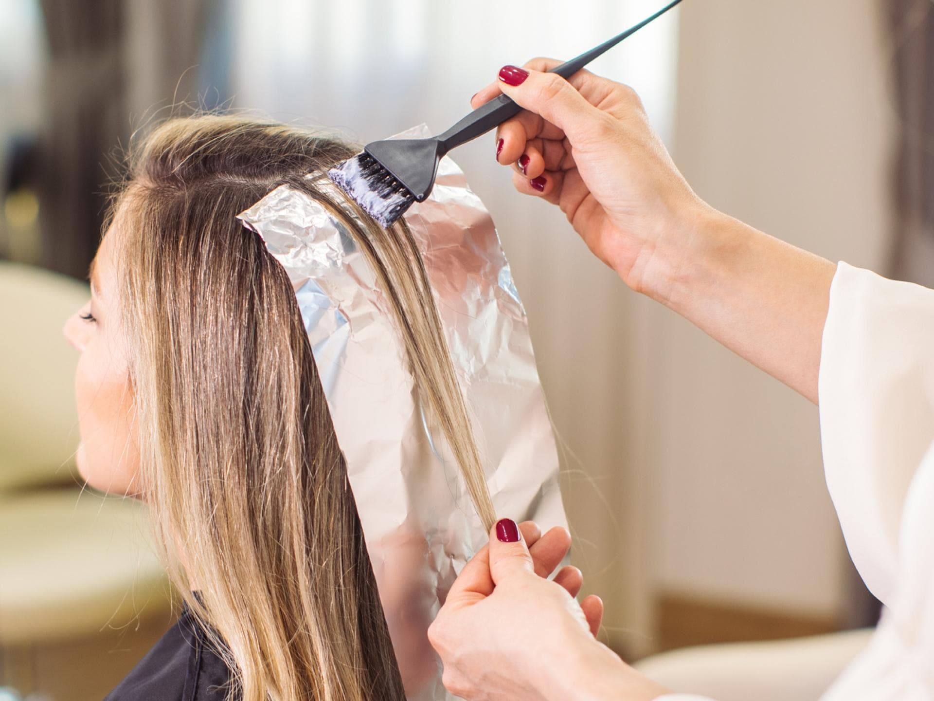 Friseur färbt Frau Haare 