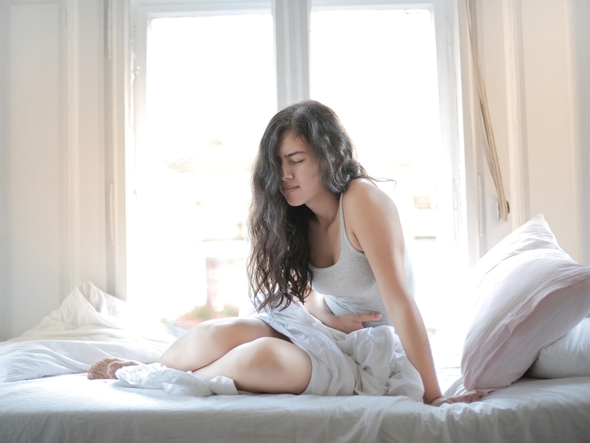 Frau mit Bauchschmerzen im Bett